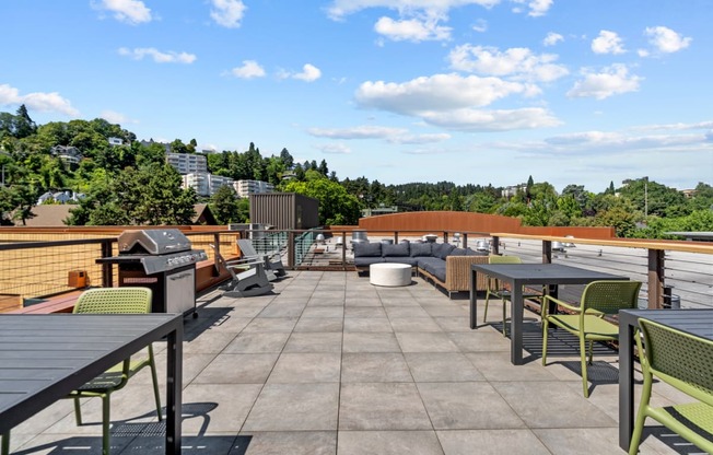 a rooftop patio with tables and chairs and a grill