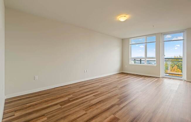 A room with wooden flooring and a large window overlooking the ocean.