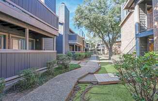 Walkways in between apartments with lush landscaping at The Pearl apartments in Shreveport, LA