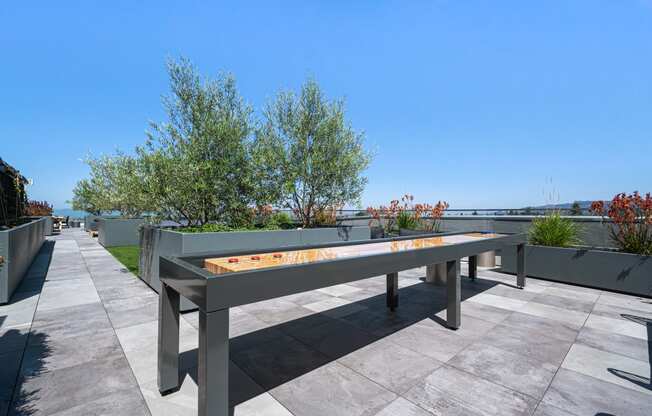 the outdoor ping pong table on the terrace of a building with trees