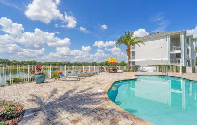 swimming pool with lounge chairs and apartment in the background