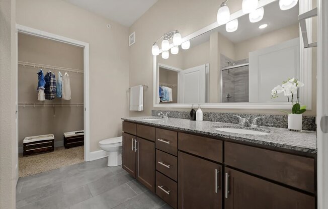 A bathroom with a large mirror and lights above it.