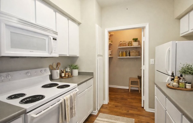 A kitchen with white cabinets and a stove top oven.