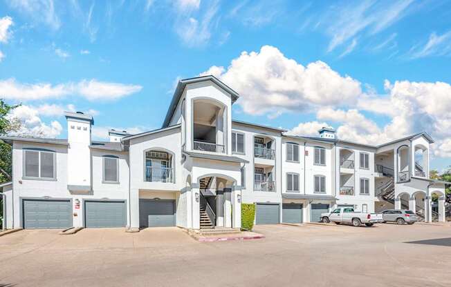 A large white building with a blue roof and a parking lot in front.
