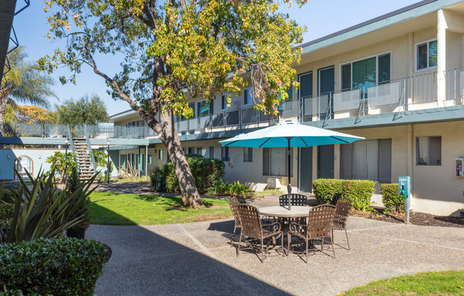 a patio with a table and chairs in front of a building