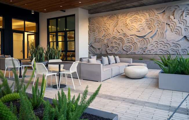 A modern outdoor seating area with a wooden ceiling and a large mural on the wall.