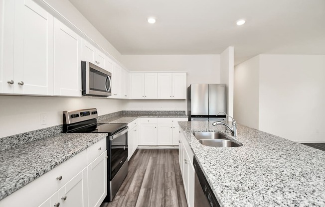 A kitchen with granite countertops and white cabinets.