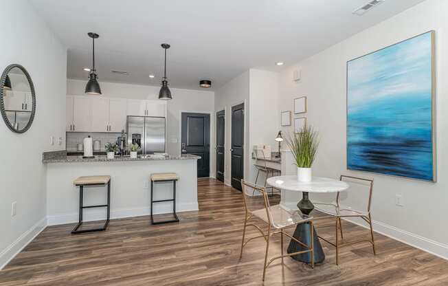 a dining area with a table and chairs and a kitchen in the background