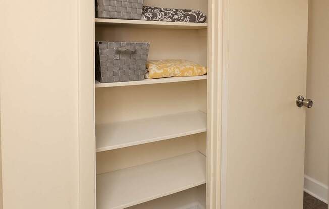 A white door is open to a hallway with a white shelving unit.