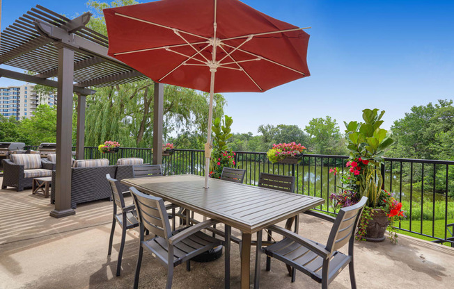 a patio with a table and chairs and a red umbrella