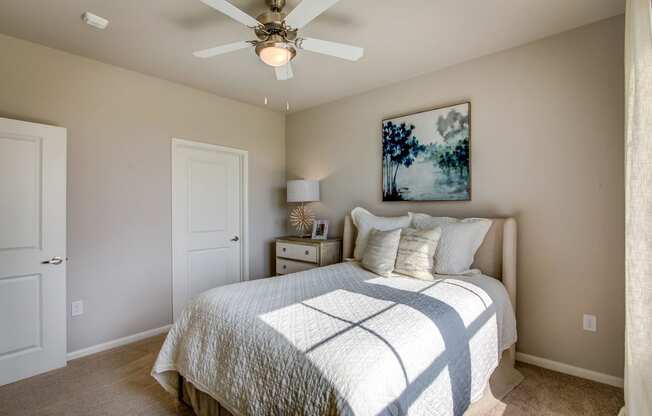 a bedroom with a ceiling fan and a bed with a white comforter