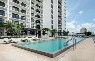 Apartments Miami FL - MB Station - Apartment Balconies Overlooking Sparkling Resort-Style Pool Surrounded by Lounge Seating