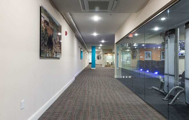 a long corridor with glass doors and a lobby with paintings on the wall