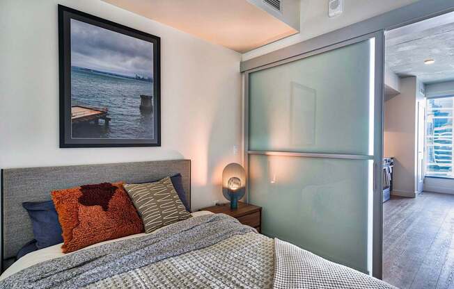 A bedroom with a bed, nightstand, and a picture on the wall.