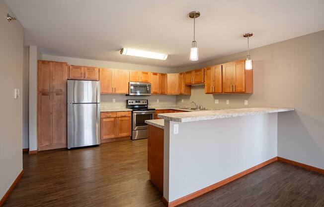 A kitchen with wooden cabinets and a white counter. Fargo, ND Urban Plains Apartments