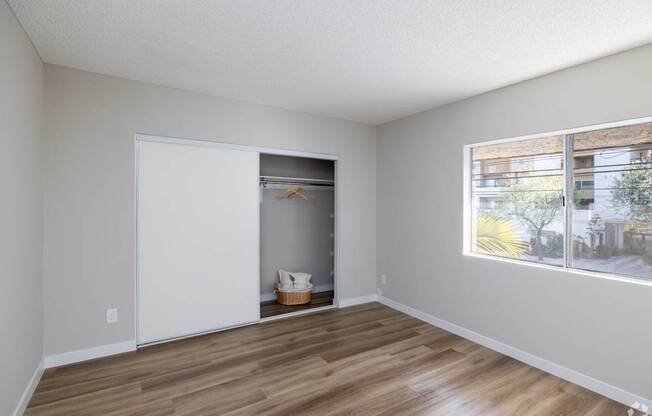 A room with a white door and a window with a view of a building outside.