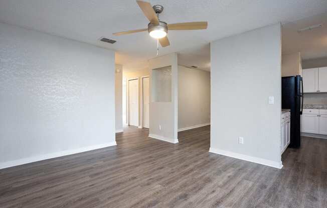 A room with a ceiling fan and wooden flooring.