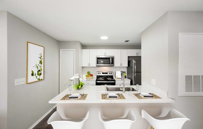 a kitchen with white cabinets and a white island with four white chairs