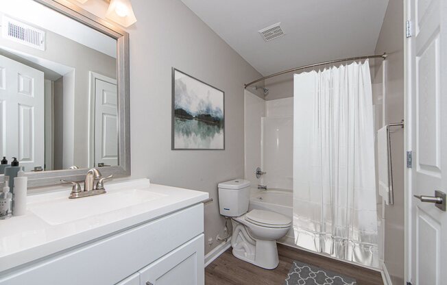 A white bathroom with a toilet, sink, and shower.