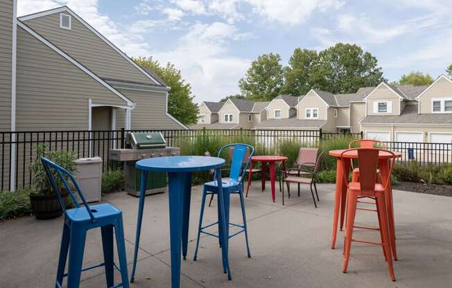 a patio with colorful chairs and tables and houses in the background