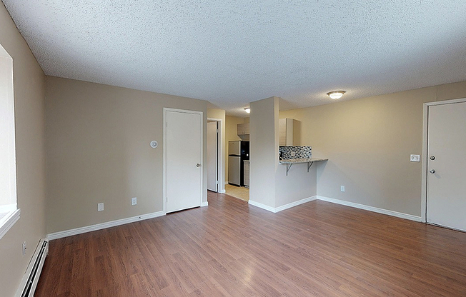 Spacious apartment with elegant hardwood floors, featuring an open-concept living area and cozy kitchen alcove.