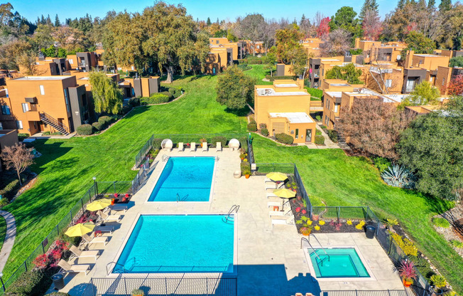 Arial view of the community with pools, spa, grassy courtyard and apartment buildings ,