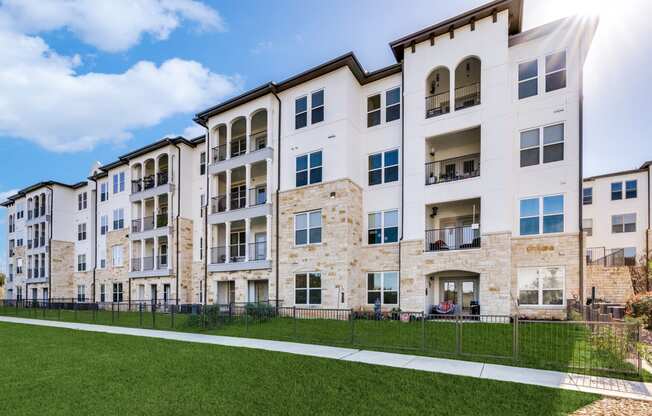 an image of an apartment building with green grass and a sidewalk