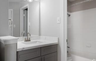 A bathroom with a sink, mirror, and toilet.