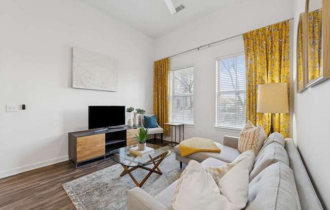 A living room with a grey couch, a wooden coffee table, and a painting on the wall.