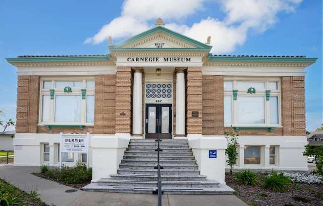 The Carnegie Museum is a two-story building with a green roof and a sign on the front.