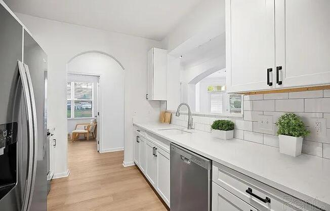 A kitchen with white cabinets and a stainless steel dishwasher.