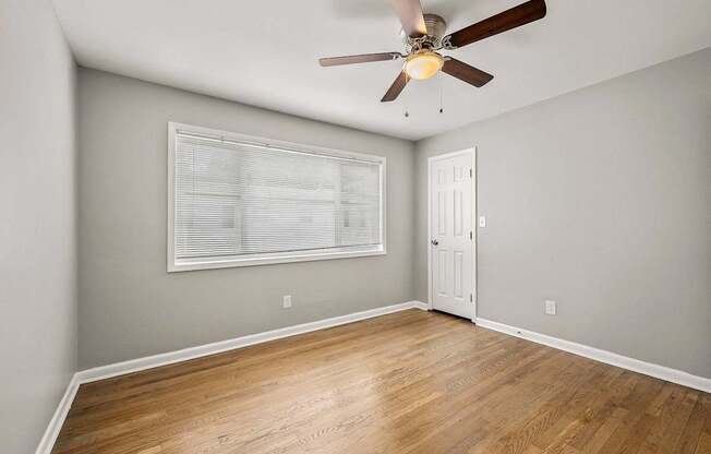A room with a ceiling fan and a window with blinds.
