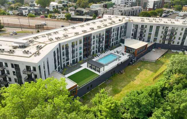 an aerial view of a large white building with a pool and tennis court in front of it