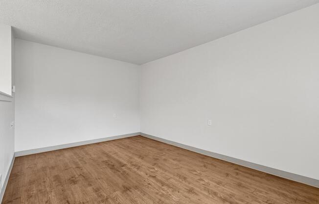 A room with wooden flooring and white walls.