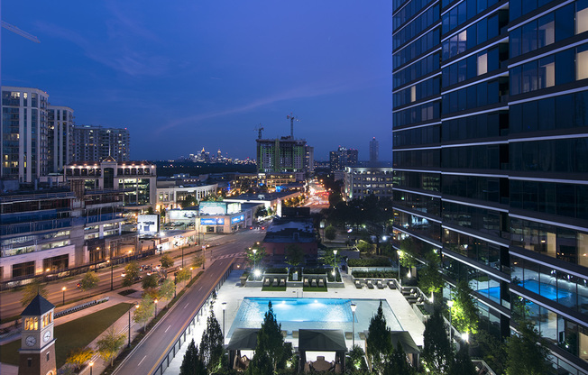 Aerial view of the 6th-floor pool deck, with tall landscaped trees in the foreground and the Midtown skyline in the background.