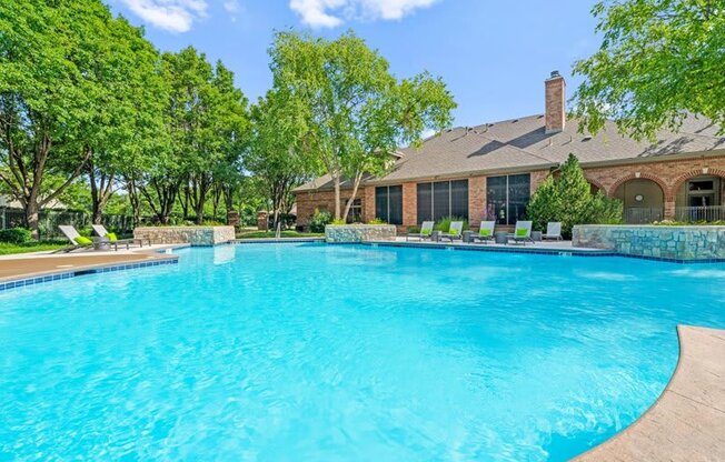 a large swimming pool with a house in the background