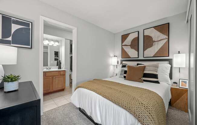 A bedroom with a bed, nightstand, and two wall art pieces.