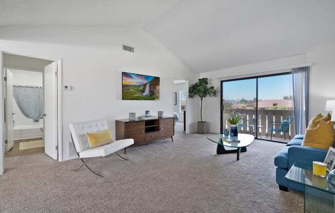 a living room with a blue couch and a white chair and a sliding glass door