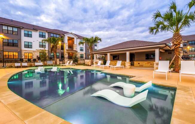 Swimming pool with chairs and a building in the background at The Parker Austin, Pflugerville, 78660