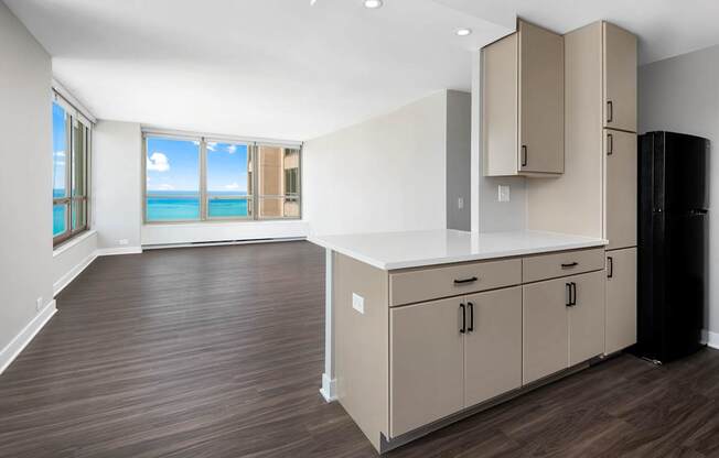 A kitchen with a black refrigerator and wooden floors.