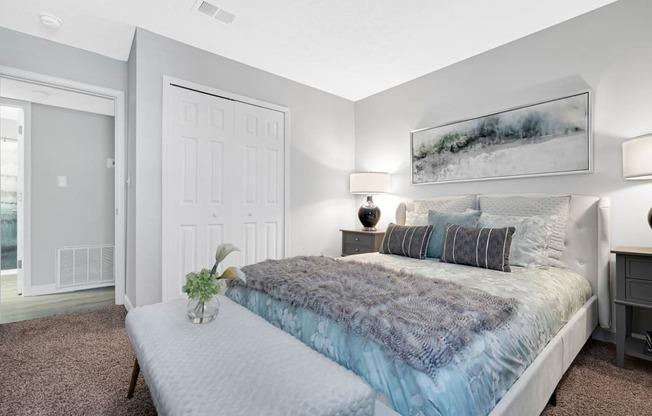 a bedroom with a bed and a nightstand with a vase of flowers on it at Stonewater Apartments, Louisville, KY