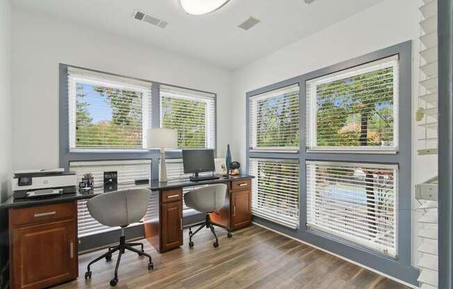 A home office with a desk, chairs, and a computer setup.