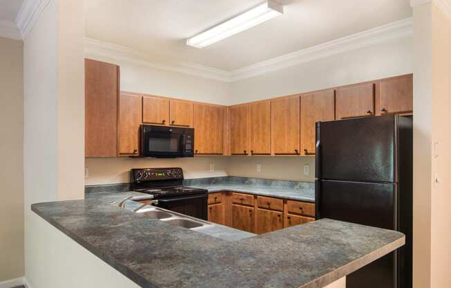 Model kitchen with elevated counter tops and black appliances at Angel Landing Apartment Homes in Pensacola, FL