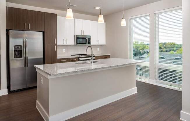 A modern kitchen with wooden floors and white and brown wood cabinets with stainless steel appliances