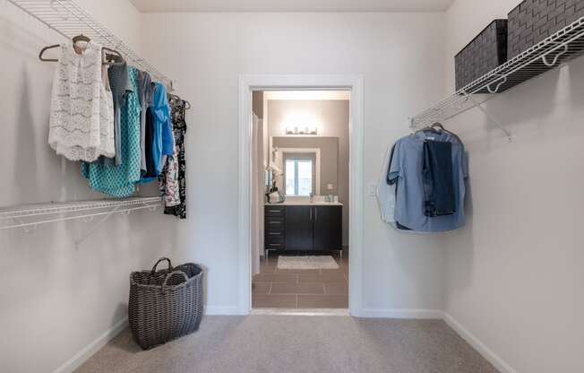 a closet with clothes hanging on the wall and a door to a bathroom