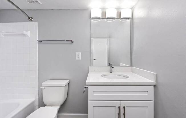 A white bathroom with a toilet, sink, and mirror.