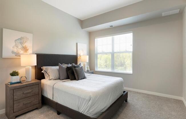 A bedroom with a large bed, nightstand, and window.