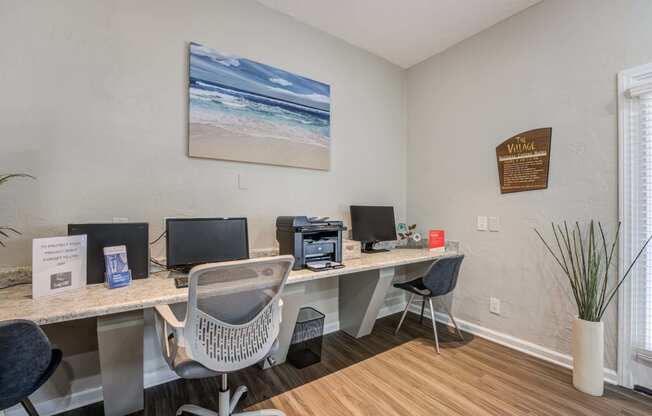 a desk with three computers and a printer on it