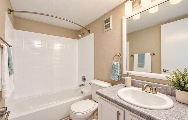 Bathroom with an oval sink and tiled bathtub surround at Waterchase Apartments in Largo, FL.