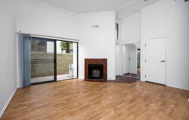 an empty living room with a fireplace and a sliding glass door